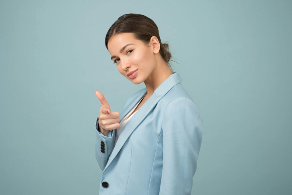 Una mujer joven con un traje azul muestra confianza con una pose relajada sobre un fondo azul.