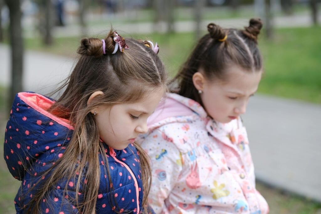 Dos chicas jóvenes con chaquetas de invierno, contemplativas en un entorno de parque.