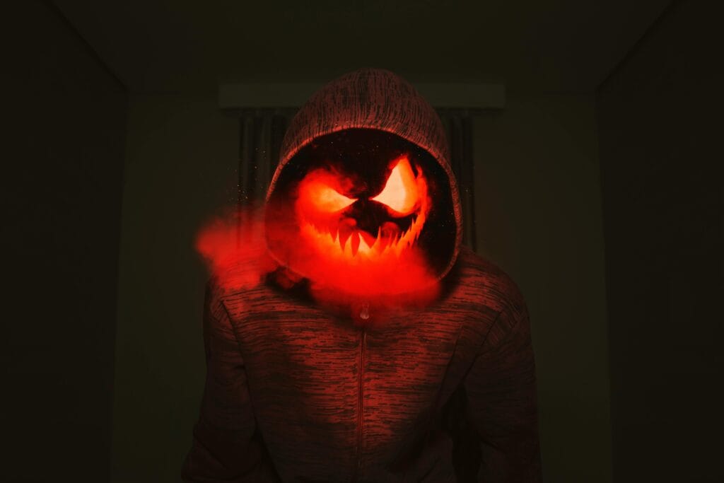 Una cabeza de calabaza espeluznante en una sudadera con capucha exuda un ambiente espeluznante de Halloween con humo rojo.