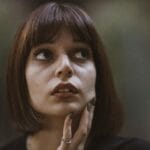 Retrato en primer plano de una mujer morena con un aspecto pensativo con una iluminación dramática y un fondo suave.