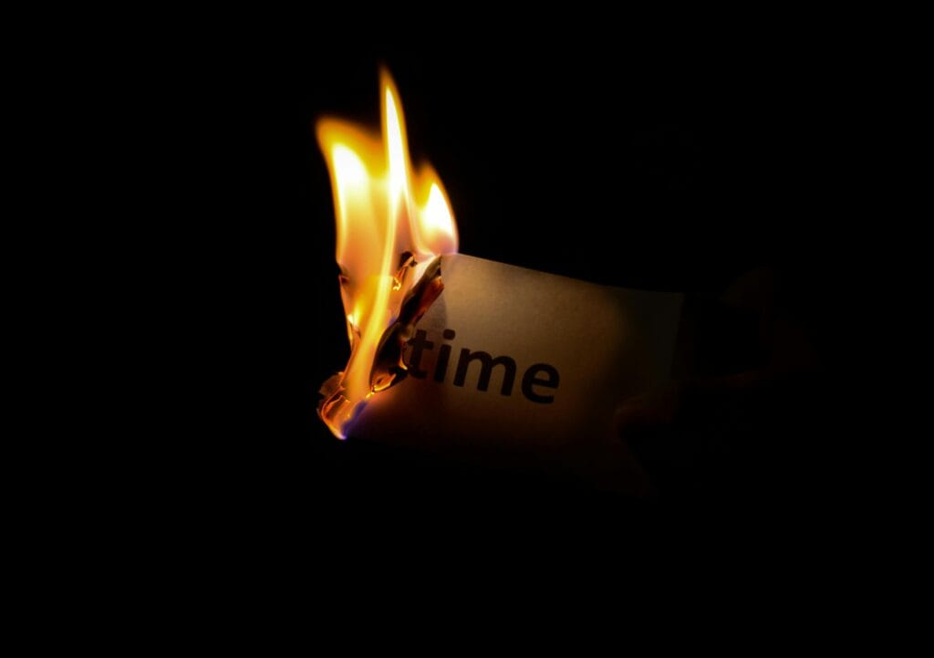 Un primer plano de un papel con la palabra "tiempo" quemando sobre un fondo oscuro.