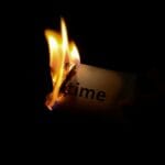 Un primer plano de un papel con la palabra "tiempo" quemando sobre un fondo oscuro.
