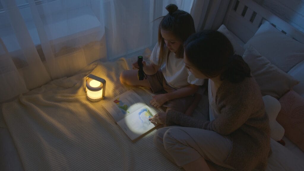 Madre e hija disfrutan de un acogedor cuento para dormir con una linterna, fomentando el vínculo familiar.
