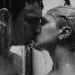 Imagen íntima en escala de grises que captura a una pareja besándose apasionadamente en una ducha.