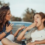 Una madre y su hijo adolescente están teniendo una conversación al aire libre. El hijo parece desinteresado.